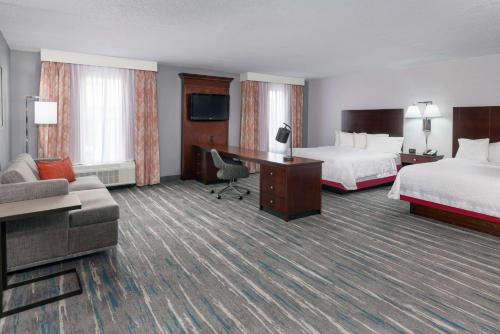 a hotel room with two beds and a desk at Hampton Inn & Suites Orlando Airport at Gateway Village in Orlando