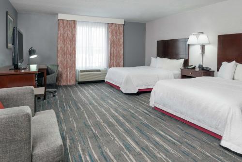 a hotel room with two beds and a desk at Hampton Inn & Suites Orlando Airport at Gateway Village in Orlando