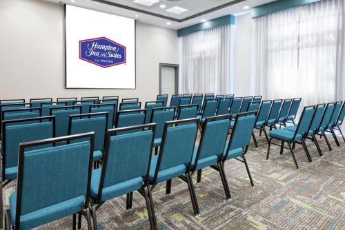 a conference room with blue chairs in front of a screen at Hampton Inn & Suites Orlando Airport at Gateway Village in Orlando