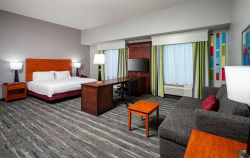 Hampton Inn & Suites Mobile I-65@ Airport Boulevard في موبايل: غرفة الفندق بسرير ومكتب واريكة