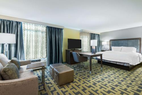 タンパにあるHampton Inn & Suites Tampa Airport Avion Park Westshoreのベッドとデスクが備わるホテルルームです。