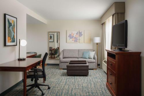 a living room with a couch and a desk with a television at Homewood Suites by Hilton Knoxville West at Turkey Creek in Knoxville