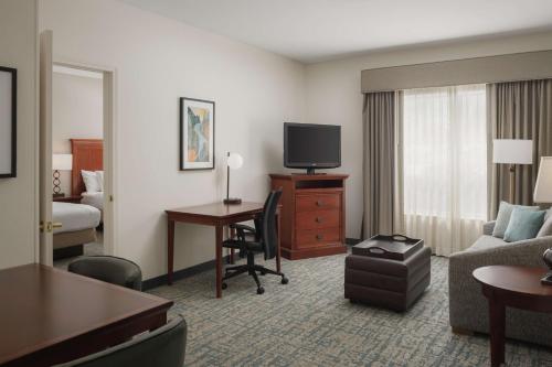 a hotel room with a couch and a desk with a television at Homewood Suites by Hilton Knoxville West at Turkey Creek in Knoxville