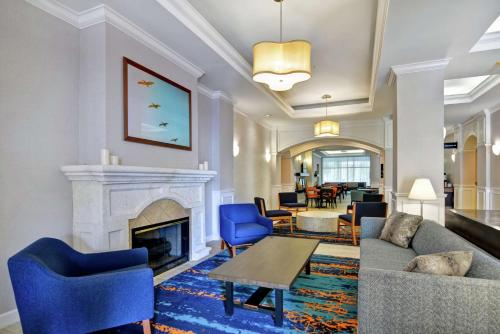 a living room with a fireplace and blue chairs at Hampton Inn Palm Beach Gardens in Palm Beach Gardens