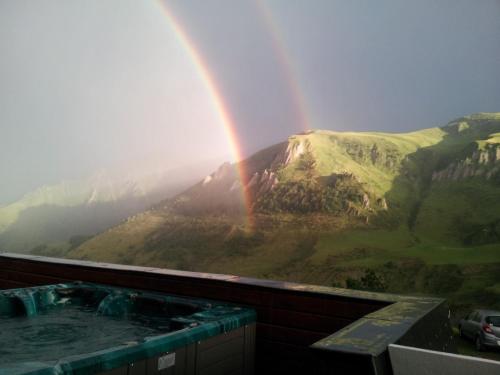 a rainbow over a mountain with a hot tub at Gîte Chalet du Soulor in Arrens-Marsous