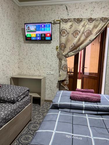 Habitación con 2 camas y TV en la pared. en Asia Minor, en Samarkand