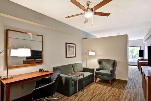 a living room with a couch and a desk and chairs at Hampton Inn Palm Beach Gardens in Palm Beach Gardens