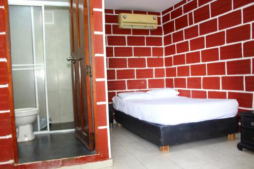 a red brick room with a bed and a shower at Hostal La Guaca in Cartagena de Indias