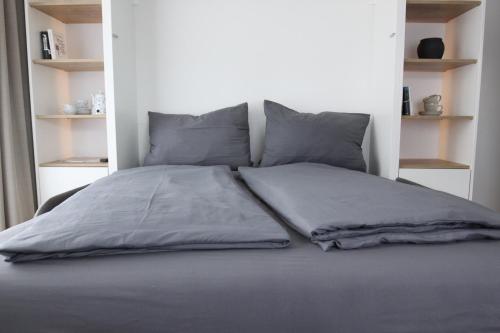 łóżko z szarą pościelą i poduszkami w obiekcie Inselbutze Borkum w mieście Borkum