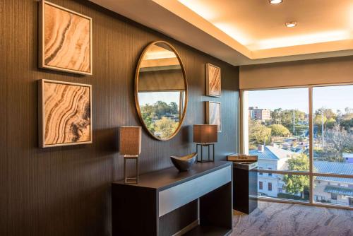 a room with a mirror and a desk and a window at Hampton Inn & Suites Tallahassee Capitol-University in Tallahassee