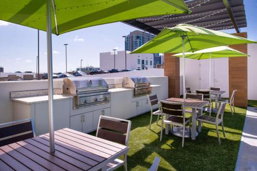 a rooftop patio with a grill and tables and umbrellas at Home2 Suites By Hilton Tampa Downtown Channel District in Tampa