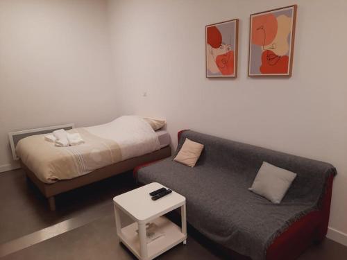 Habitación pequeña con cama y sofá en Grand studio au calme - Dijon centre, en Dijon