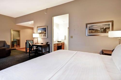 Cette chambre comprend un grand lit blanc et un bureau. dans l'établissement Homewood Suites by Hilton Cincinnati-Milford, à Milford