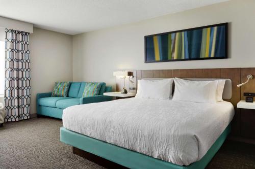 a hotel room with a bed and a blue chair at Hilton Garden Inn Cincinnati Northeast in Loveland