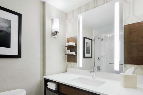 Hilton Garden Inn Cincinnati Northeast في Loveland: حمام أبيض مع حوض ومرآة