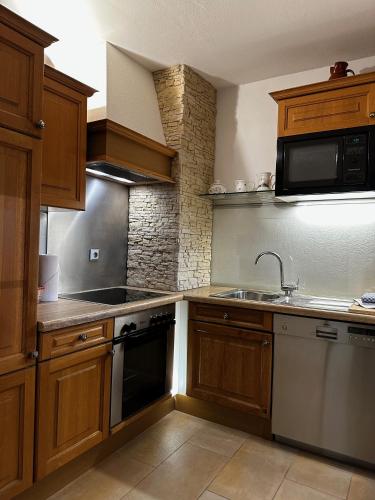 a kitchen with wooden cabinets and a sink and a microwave at Appartementhaus Birkenwald in Seefeld in Tirol