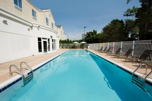 a swimming pool with chairs and a building at Hilton Garden Inn Solomons in Dowell