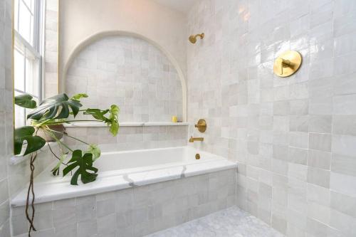 a white bathroom with a tub and a plant at Spacious 3 BDR Home With Parking Hosted By StayRafa 1121 in Philadelphia