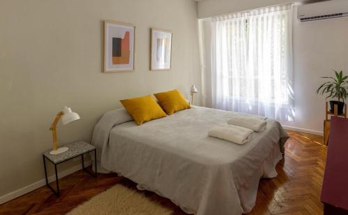 Un dormitorio con una cama con almohadas amarillas y una ventana en Junin 1400 - Recoleta Mall en Buenos Aires