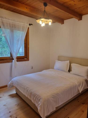 Schlafzimmer mit einem großen weißen Bett und einem Fenster in der Unterkunft Cabana rustica de vacanta in Braşov