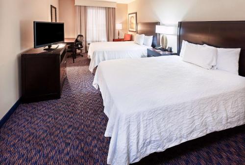 a hotel room with two beds and a flat screen tv at Hilton Garden Inn Midland in Midland