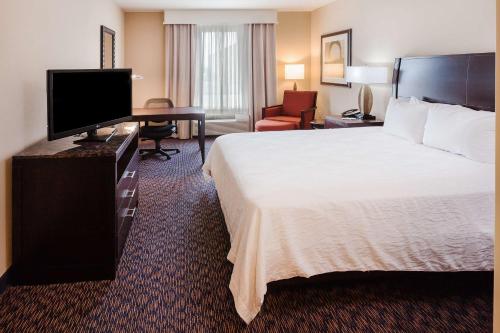 a hotel room with a bed and a desk with a television at Hilton Garden Inn Midland in Midland