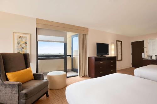 a hotel room with a bed and a chair and a television at Hilton Miami Airport Blue Lagoon in Miami