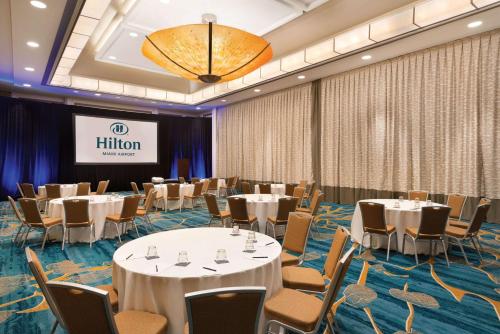 a conference room with tables and chairs and a screen at Hilton Miami Airport Blue Lagoon in Miami