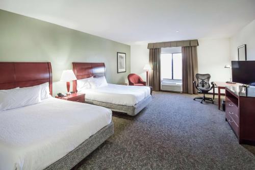 a hotel room with two beds and a flat screen tv at Hilton Garden Inn Phoenix/Avondale in Avondale