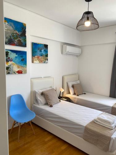 een slaapkamer met 2 bedden en een blauwe stoel bij 2 BD Top Floor Aprt with Acropolis view in Athene