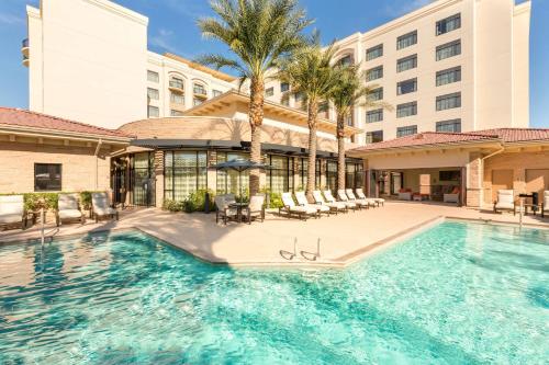 einen Pool in einem Hotel mit Stühlen und einem Gebäude in der Unterkunft Hilton Phoenix Chandler in Chandler