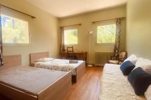 Cette chambre comprend deux lits, un bureau et deux fenêtres. dans l'établissement Rare pearl with garden near Arcachon, à La Teste-de-Buch