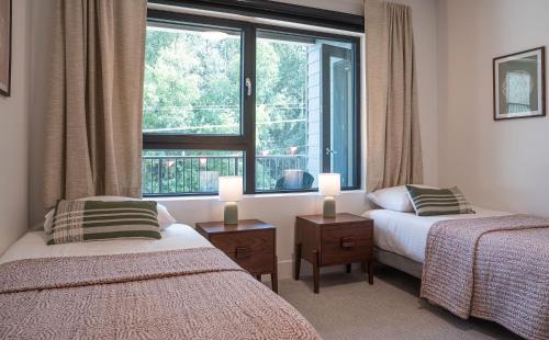 a bedroom with two beds and a large window at Forever Young by Revelstoke Vacations in Revelstoke