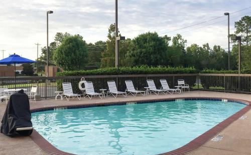 a swimming pool with lounge chairs and an umbrella at Hampton Inn Troy in Troy