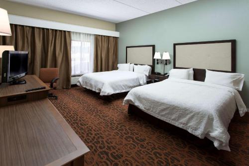 a hotel room with two beds and a flat screen tv at Hampton Inn Troy in Troy