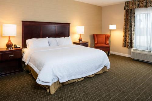 a hotel room with a large bed and a chair at Hampton Inn & Suites Toledo-Perrysburg in Rossford
