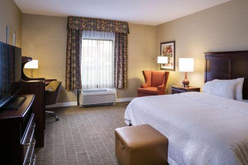a hotel room with a bed and a chair at Hampton Inn & Suites Toledo-Perrysburg in Rossford