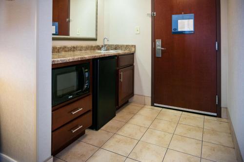 a kitchen with a sink and a tv and a door at Hampton Inn & Suites Toledo-Perrysburg in Rossford