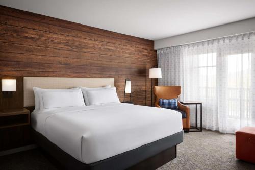 a bedroom with a white bed and a wooden wall at Killington Mountain Lodge, Tapestry Collection by Hilton in Killington
