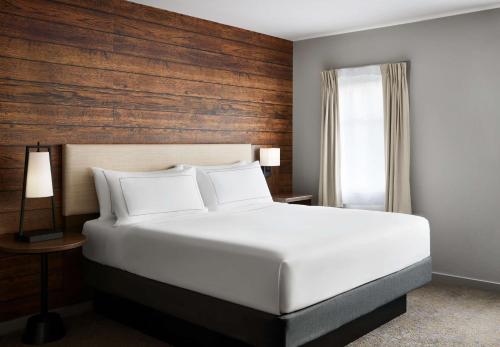 a bedroom with a white bed and a wooden wall at Killington Mountain Lodge, Tapestry Collection by Hilton in Killington
