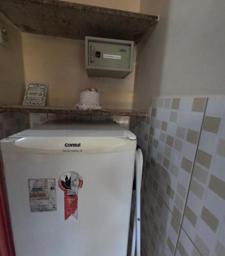 a white refrigerator in a kitchen with a shelf on top at Pousada Pedacinho de Céu in Abraão
