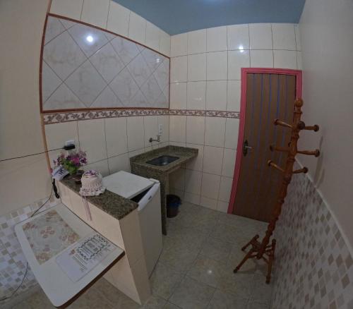 a small bathroom with a sink and a red door at Pousada Pedacinho de Céu in Abraão