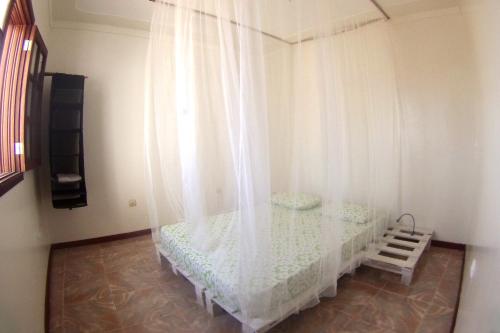 1 dormitorio con 1 cama con cortina blanca en Self-catering Apartment w/ Terrace, en Tarrafal