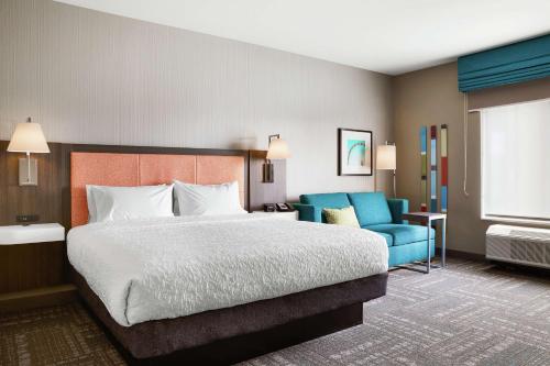 a hotel room with a bed and a blue chair at Hampton Inn & Suites Chicago/Waukegan in Waukegan