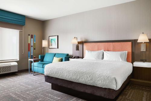 Habitación de hotel con cama y sofá azul en Hampton Inn & Suites Chicago/Waukegan, en Waukegan