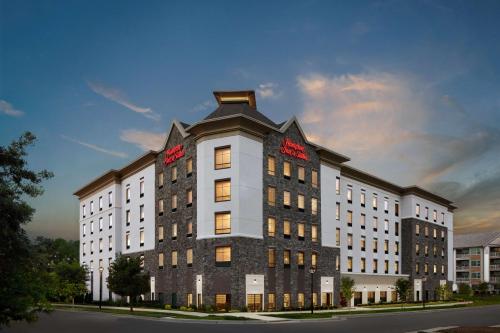 a large white building with red signs on it at Hampton Inn & Suites Charlotte Steele Creek Road, NC in Charlotte