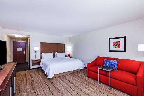 Habitación de hotel con cama y sofá rojo en Hampton Inn & Suites Houston I-10 West Park Row, Tx, en Katy