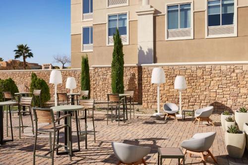 a patio with tables and chairs in front of a brick wall at Hilton Garden Inn Las Vegas/Henderson in Las Vegas