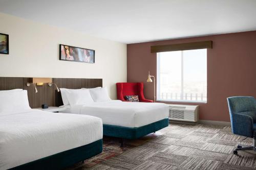 Hilton Garden Inn Las Vegas/Henderson في لاس فيغاس: غرفة فندقية بسريرين وكرسي احمر