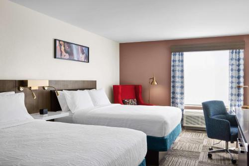 a hotel room with two beds and a red chair at Hilton Garden Inn Las Vegas/Henderson in Las Vegas